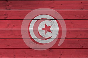 Tunisia flag depicted in bright paint colors on old wooden wall. Textured banner on rough background