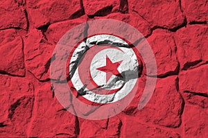 Tunisia flag depicted in paint colors on old stone wall closeup. Textured banner on rock wall background