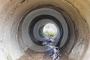 Tunnel made of reinforced concrete pipes for drainage of rainwater under the road. View through a large pipe