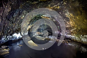 The tunnel of an old abandoned mine with rusty remnants of trolleys