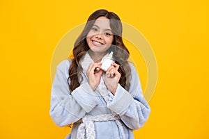 Tunny nose and allergy, nasal spray. Teen girl in pajama use nasal drops, stuffed nose isolated on yellow background.