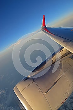 Turbine Engine, wing and red winglet with white clouds and deep blue sky in the background