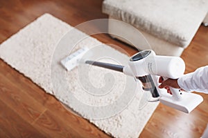 The turbo brush of a cordless vacuum cleaner cleans the carpet in the house in close-up