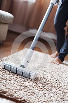 The turbo brush of a cordless vacuum cleaner cleans the carpet in the house in close-up