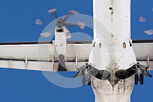Turboprop aircraft flies overhead, view of the landing gear, wing and engine