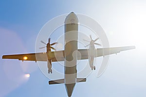 Turboprop airplane in the sky from underneath with sun rays