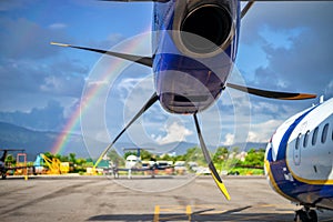 Turboprop engine of an aircraft on tarmac against the rainbow
