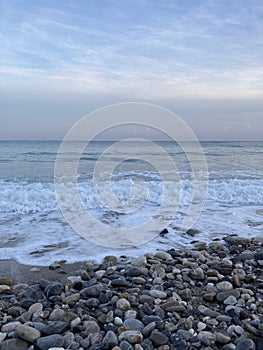 The turbulent sea storms the shore of sand mixed with pebbles