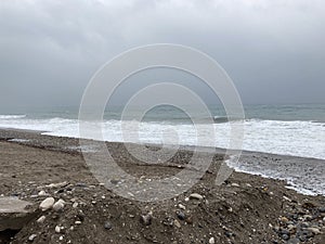 The turbulent sea storms the shore of sand mixed with pebbles