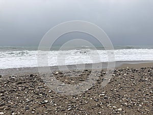 The turbulent sea storms the shore of sand mixed with pebbles