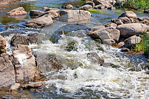 A turbulent stream of water swiftly sweeps through the stone boulders of the river rapids