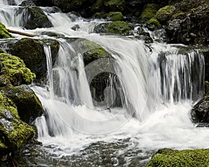 Turbulent waterfall rushing over a steep cliff at a popular toursit destination, with mossy rocks.