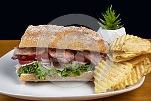 turkey with blt on ciabatta bread, and a side of chips photo