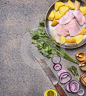 Turkey breast with pears and potatoes on a vintage pan with red onion and herbs with knife for meat and various spices on a gran