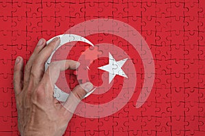 Turkey flag is depicted on a puzzle, which the man`s hand completes to fold