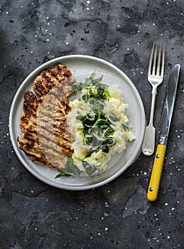 Turkey grilled chop and mashed potatoes with butter spinach on a dark background, top view. Comfort winter autumn home cooked food