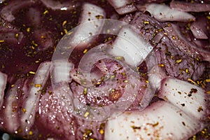 Turkey meat cut into pieces and marinated in red wine with onions and spices. Close-up, surface texture