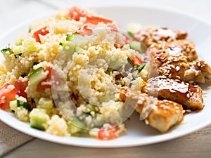 Turkey meat, fried, with teriyaki sauce and sesame seeds. A side dish of Couscous with vegetables.
