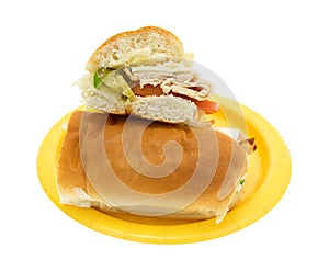 Turkey sub sandwich halved on a yellow paper plate