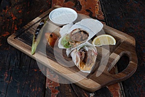 Turkish and Arabic traditional Ramadan Adana kebab roll wrap serving with yogurt and hot pepper  on rustic wooden backgrou