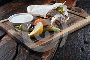 Turkish and Arabic traditional Ramadan Adana kebab roll wrap serving with yogurt and hot pepper on rustic wooden background