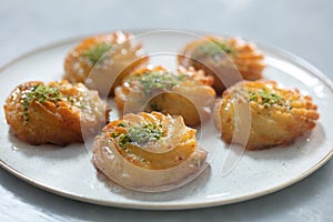 Turkish and Arabic Traditional Ramadan Dessert Lor Cheese Dessert with pistachio powder and syrup serving on plate.