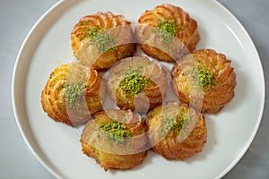 Turkish and Arabic Traditional Ramadan Dessert Lor Cheese Dessert with pistachio powder and syrup serving on plate.