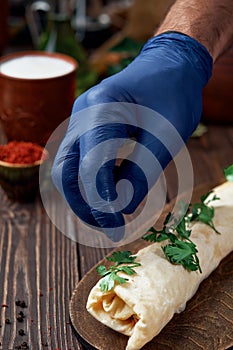 Turkish and arabic traditional roll adana kebab with vegetable salad on rustic wooden background. The chef sprinkles the kebab