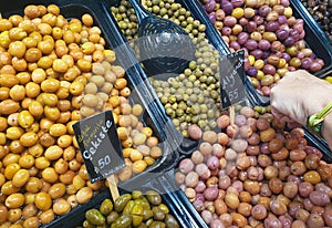 Turkish assortment of ripe pickled green olives on the counter of a seller in food bazaar.