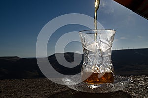 Turkish Azerbaijan tea in traditional glasse and pot outdoor nature background with sunlight and smoke. Eastern tea concept. Armud