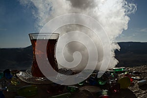 Turkish Azerbaijan tea in traditional glasse and pot outdoor nature background with sunlight and smoke. Eastern tea concept. Armud