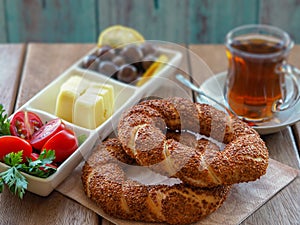 Turkish bagel on wooden table, tea and breakfast plate. Tomatoes, cheese, olives