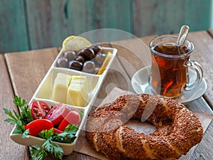 Turkish bagel on wooden table, tea and breakfast plate. Tomatoes, cheese, olives