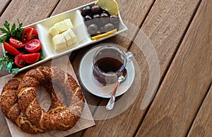 Turkish bagel on wooden table, tea and breakfast plate. Tomatoes, cheese, olives