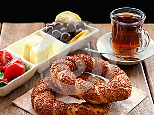Turkish bagel on wooden table, tea and breakfast plate. Tomatoes, cheese, olives