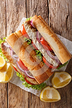 Turkish Balik Ekmek sandwich with grilled mackerel and vegetables close-up on the table. Vertical top view