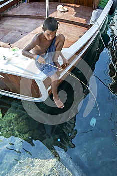 A Turkish boy fishing from a boat.