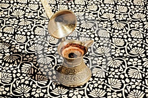 Turkish Cezve with fresh coffee on the tablecloth
