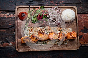 Turkish chicken sis kebab with rice and vegetables on rustic wooden table