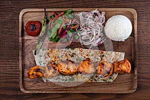 Turkish chicken sis kebab with rice and vegetables on wooden table