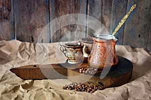 Turkish coffee background with copper coffee pot, cups and coffee beans on a wooden desk