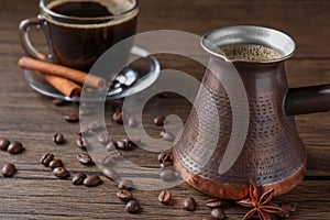 Turkish coffee in cezve and cup, beans and spices on wooden table. Space for text