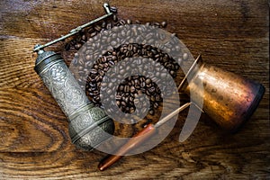 Turkish coffee concept. Copper coffee pot Cezve, vintage coffee grinder, cup, coffee beans on a dark wooden background. Top view