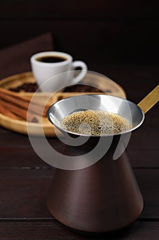 Turkish coffee pot with hot drink on wooden table