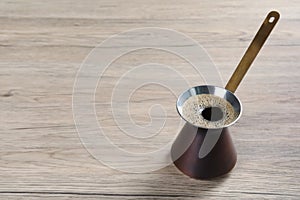 Turkish coffee pot with hot drink on wooden table, space for text