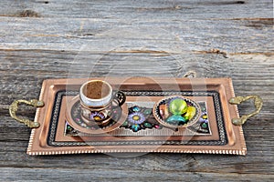 Turkish coffee. Pouring Turkish coffee into vintage cup on wooden background. Pouring Turkish coffee into traditional embossed