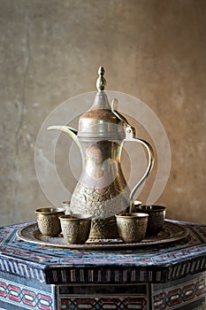 Turkish coffee set: Ottoman ornate coffee pot and small ornate cups on decorated tray and decorated Arabic style table