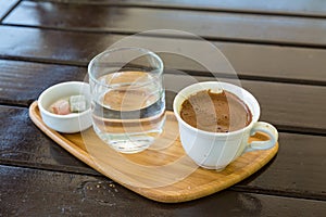 Turkish coffee on the wood with glass of water and turkish delights