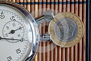 Turkish coin with a denomination of one lira and stopwatch on wooden table - back side