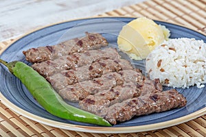 Turkish cuisine inegol meatballs. Grilled meatballs on a plate. Turkish Tekirdag or inegol Kofte with pepper, rice and mashed